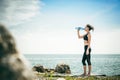 woman drinking water from a bottle on the beach on a warm summer day, exercise in open air Royalty Free Stock Photo