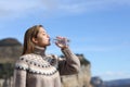 Woman drinking water from bottle in winter in the mountain