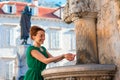 Woman drinking water from classical fountain in