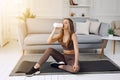 Woman drinking water at the home. Muscular woman taking break after exercise.