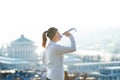 Woman drinking water during a running. Cold weather. Jogging woman in a city during a winter. Sunny day. Drinking mode. Royalty Free Stock Photo