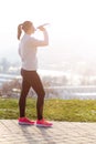 Woman drinking water during a running. Cold weather. Jogging woman in a city during a winter. Sunny day. Drinking mode. Royalty Free Stock Photo