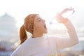 Woman drinking water during a running. Cold weather. Jogging woman in a city during a winter. Sunny day. Drinking mode. Royalty Free Stock Photo