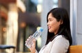 Woman drinking water sitting on wooden city bench Royalty Free Stock Photo