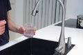 Woman drinking from water tap or faucet in kitchen. Pouring fresh water. Healthy lifestyle. Water quality check concept. The Royalty Free Stock Photo