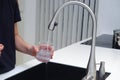 Woman drinking from water tap or faucet in kitchen. Pouring fresh water. Healthy lifestyle. Water quality check concept. The Royalty Free Stock Photo