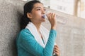 woman drinking water to rehydrate to avoid heat stroke after running outdoors in the summer