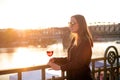 Woman drinking a wine in the city during a sunset. Glass of red wine. Concept of free time in the city and drinking alcohol.