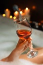 Woman drinking wine while taking bubble bath, closeup. Romantic atmosphere Royalty Free Stock Photo