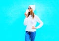 woman drinks coffee in white sweater, hat on a blue background Royalty Free Stock Photo