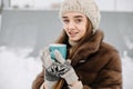 Woman Drinks Hot Tea or Coffee From a Cozy Cup on Snowy Winter Morning Outdoors. Beautiful Girl Enjoying Winter in a Garden with a Royalty Free Stock Photo