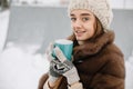 Woman Drinks Hot Tea or Coffee From a Cozy Cup on Snowy Winter Morning Outdoors. Beautiful Girl Enjoying Winter in a Garden with a Royalty Free Stock Photo