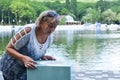 Woman drinks spring water from fountain. Drinking mineral water in fresh air.