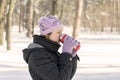 woman drinks tea out of cup. Winter forest. Young man in a red warm jacket with knitted hat and scarf standing on snowy background Royalty Free Stock Photo