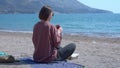 Woman drinks tea from thermos resting on sea sand beach Royalty Free Stock Photo