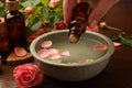 Woman dripping essential oil into bowl at wooden table, closeup. Aromatherapy treatment Royalty Free Stock Photo