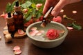 Woman dripping essential oil into bowl at wooden table, closeup. Aromatherapy treatment Royalty Free Stock Photo