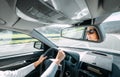 Woman drive a car reflects in back view mirror