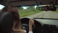 Woman driver hand on a steering wheel no blurred background of a road in summer time on the city road. Handheld of woman back driv