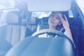 Woman driver looking at rear view mirror and correcting the hairstyle and makeup while driving the car Royalty Free Stock Photo