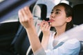 Woman driver looking at rear view mirror and correcting the makeup while driving the car Royalty Free Stock Photo