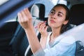 Woman driver looking at rear view mirror and correcting the makeup while driving the car Royalty Free Stock Photo