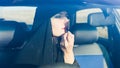 Woman driver paints lips in the car looks in the mirror