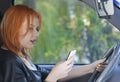 Woman driver sending sms on phone while driving Royalty Free Stock Photo