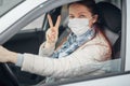 A woman driving a car puts on a medical mask during an epidemic, a taxi driver a woman in a mask, protection from the virus