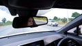 Woman driving car reflects in rear view mirror Royalty Free Stock Photo