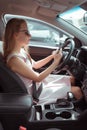 A woman driving car, sitting in mobile phone, writing message in parking lot near shopping center, waiting for friends Royalty Free Stock Photo