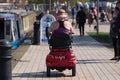 Woman driving mobility scooter wearing sun hat