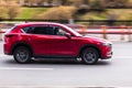 Woman is driving red Mazda CX-5 on the street. SUV car in motion on the city road. Compliance with speed limits on road concept