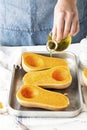 Woman drizzling olive oil over butternut squash before baking Royalty Free Stock Photo