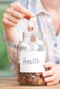 Woman Dropping Coins Into Glass Jar Labelled Health Royalty Free Stock Photo