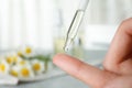 Woman dropping essential oil on finger over table