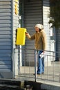 Woman dropping letter into yellow postal box