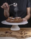 A woman drops icing sugar onto a donut using a duster Royalty Free Stock Photo