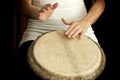 Woman drumming on goat skin bongo drum