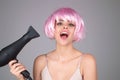 Woman drying her hair with a hairdryer isolated on studio background. Girl with blow dryer drying hair, making hairdo Royalty Free Stock Photo