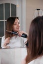 Woman drying her hair, styling in the bathroom near mirror Royalty Free Stock Photo