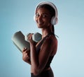 Woman, dumbbells and music headphones for workout in studio on blue background for yoga mat training, exercise or