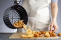 A woman is dumping fresh made potato waffle fries from basket onto a countertop