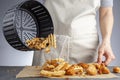 A woman is dumping fresh made potato waffle fries from basket onto a countertop