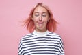 Woman with dyed pink hair doing facial expression and touching nose with tongue