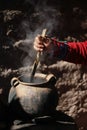 Woman dyeing wool in clay pot for weaving