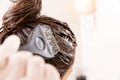 Woman dying her hair with brush in front of mirror in her own bathroom.