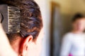 Woman dying her hair with brush in front of mirror in her own bathroom