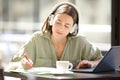 Woman e-learning with laptop and headphones taking notes Royalty Free Stock Photo