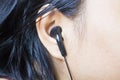 Woman ear with black earphone, Black earphone in girl's ear Royalty Free Stock Photo